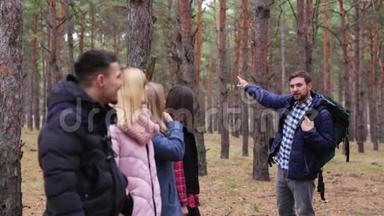 一群穿着秋装的游客正站在树林里，听着一个森林人的话。